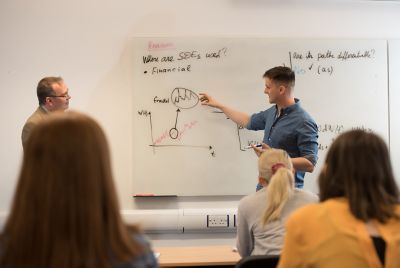 Group of undergraduate students sat at table discussing whilst writing notes